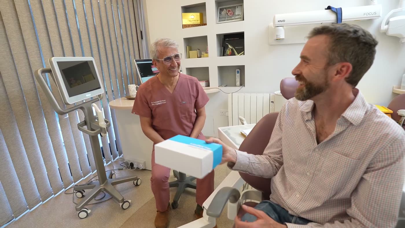 Dentist handing a patient his Invisalign aligners